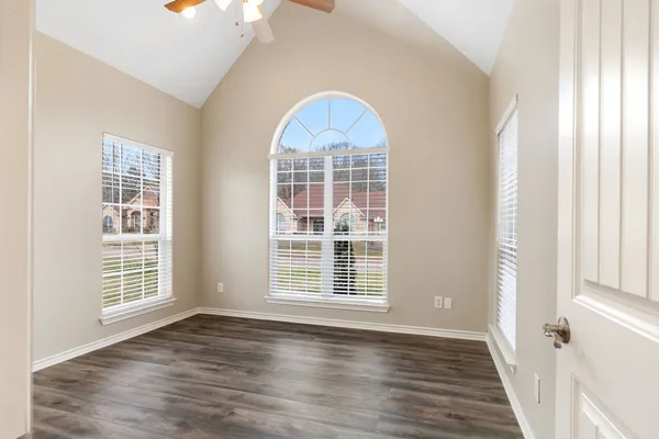 an empty room with wooden floor exposed radiator and windows