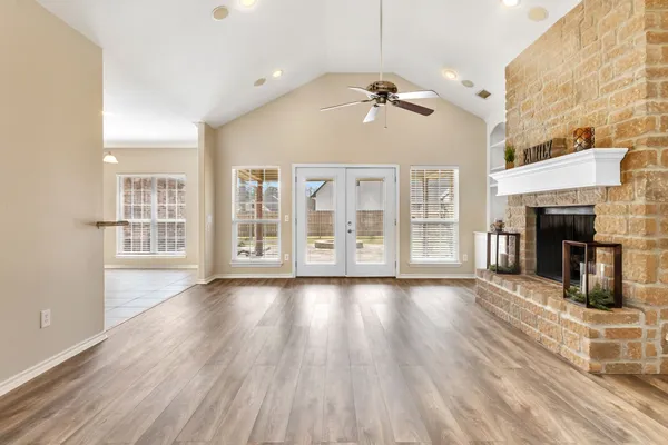 a view of an empty room with wooden floor and fireplace