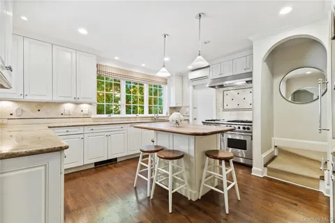 a kitchen with granite countertop a stove a sink a dining table and chairs with wooden floor