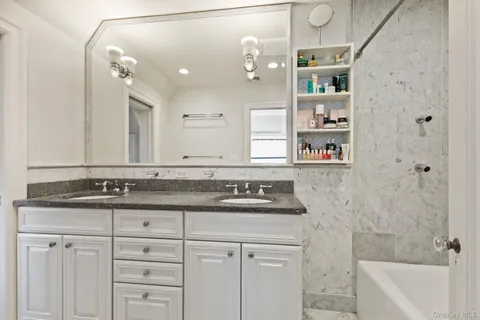 a bathroom with a granite countertop sink a mirror and a bathtub