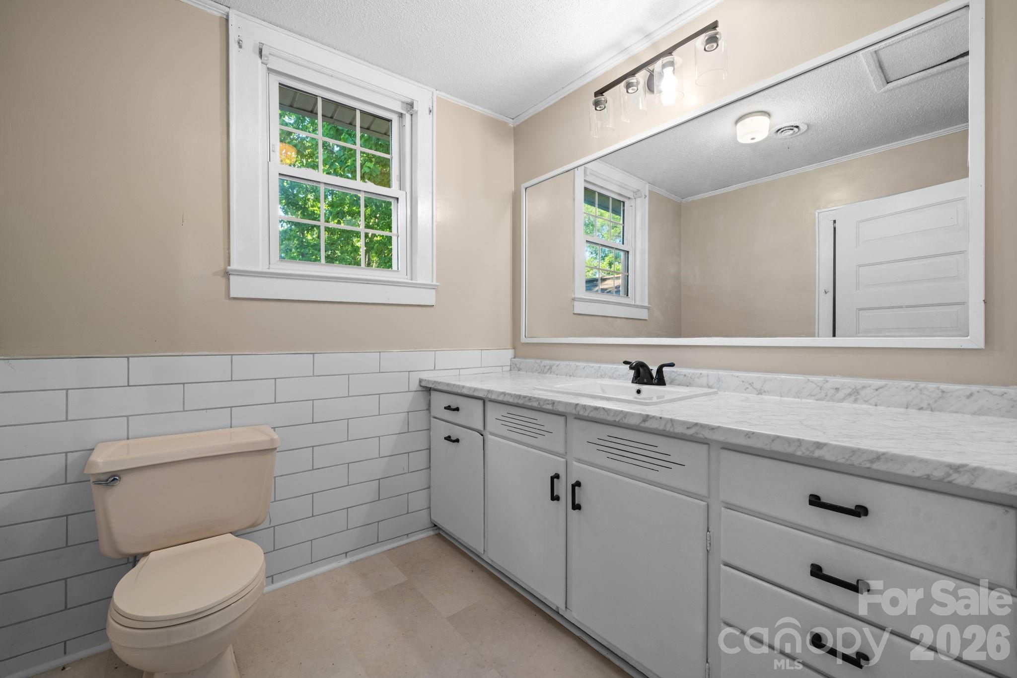144 Hunter Bridge Road Stony Point, NC 28678 - Photo 26 of 45 a bathroom with a granite countertop toilet a sink a mirror and a window