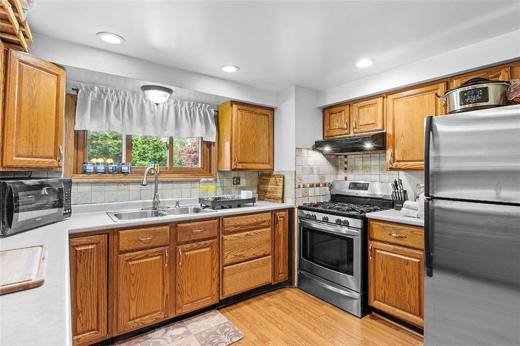 33 Radium Street Pittsburgh, PA 15214 - Photo 11 of 31 a kitchen with stainless steel appliances granite countertop a stove a sink dishwasher a refrigerator and cabinets with wooden floor