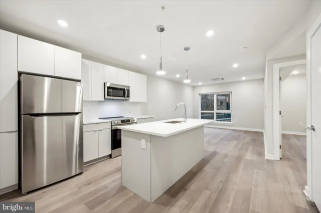 a kitchen with stainless steel appliances granite countertop a refrigerator a stove a sink dishwasher and a refrigerator with wooden floor