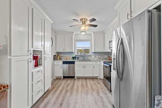 a kitchen with cabinets stainless steel appliances a sink a stove and a window