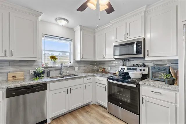 a kitchen with cabinets stainless steel appliances and a wooden floor