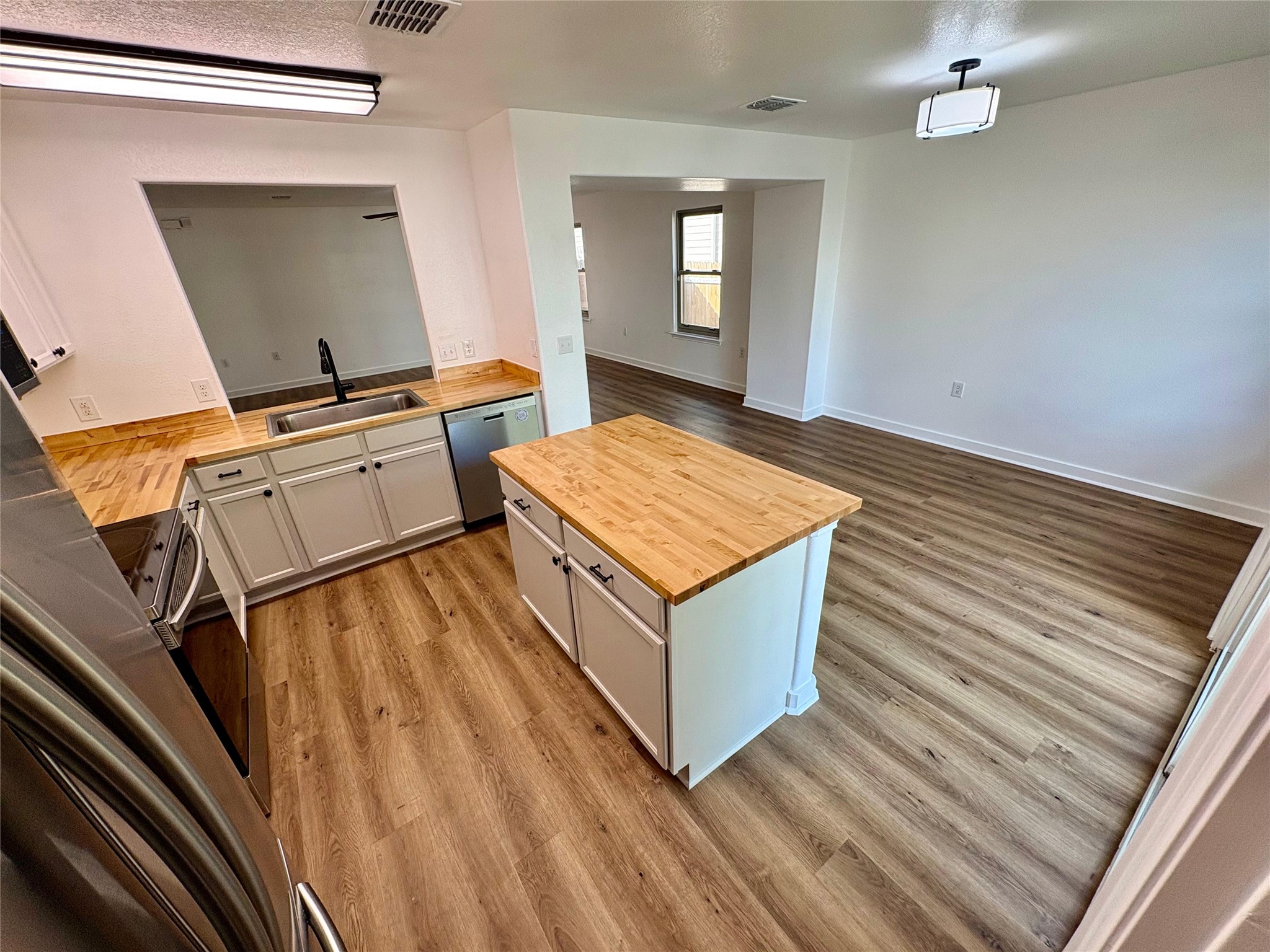 8003 Bannock Lane Austin, TX 78747 - Photo 39 of 40 Kitchen featuring wooden counters, a kitchen island, light wood-type flooring, open floor plan, and dishwasher