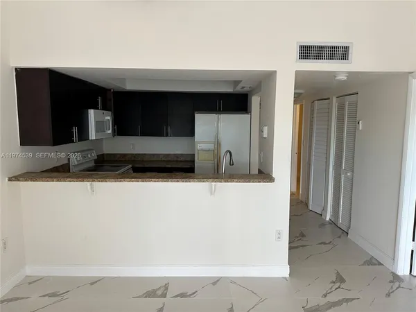 a living room with a bed and a refrigerator
