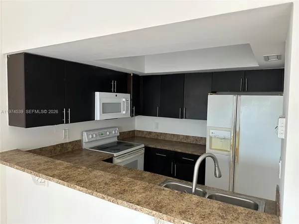 a kitchen with stainless steel appliances kitchen island granite countertop a refrigerator and a sink