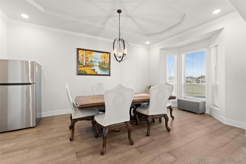 600 St Andrew Lane Prosper, TX 75078 - Photo 11 of 29 Dining space featuring ornamental molding, light wood-type flooring, a raised ceiling, and hanging lights