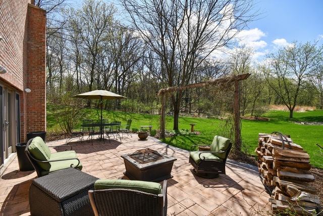 37W571 Grey Barn Road St. Charles, IL 60175 - Photo 23 of 31 a view of a patio with couches table and chairs under an umbrella with large trees