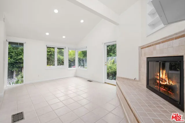 an empty room with windows and fireplace