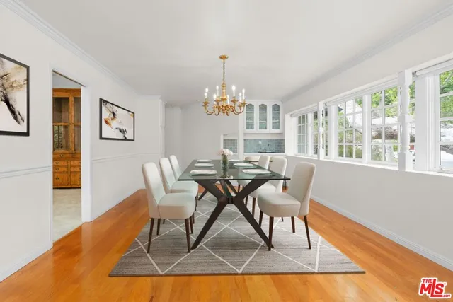a dining room with wooden floor a chandelier a glass table and chairs