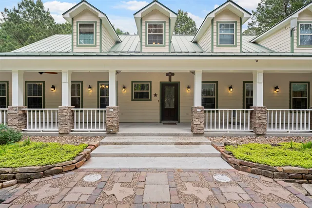 a view of a house with a yard plants and large trees