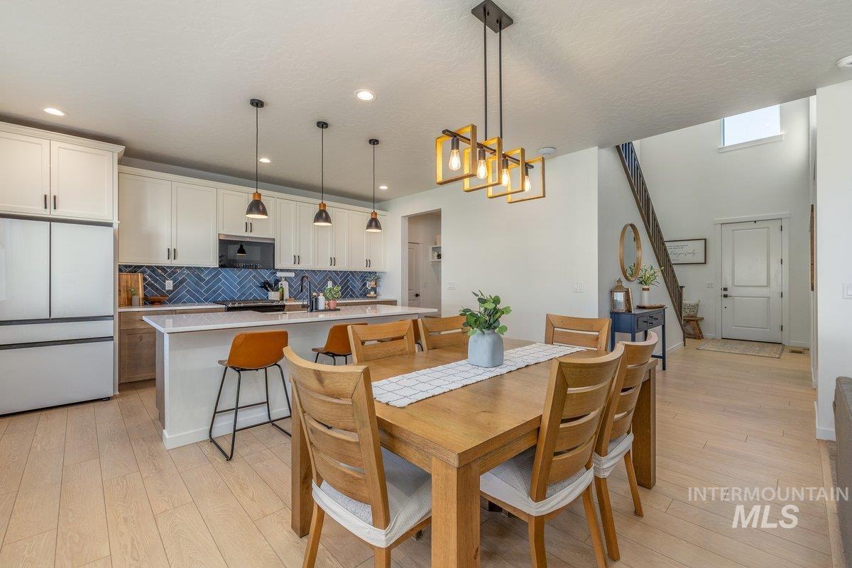1380 West Chilitna Street Meridian, ID 83642 - Photo 17 of 50 Open-concept living space featuring wood-finish flooring, a contemporary kitchen island with a light-colored countertop, and a striking blue herringbone tile backsplash