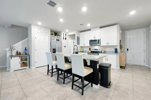 a kitchen with stainless steel appliances granite countertop a stove a sink a refrigerator and a dining table with wooden cabinets