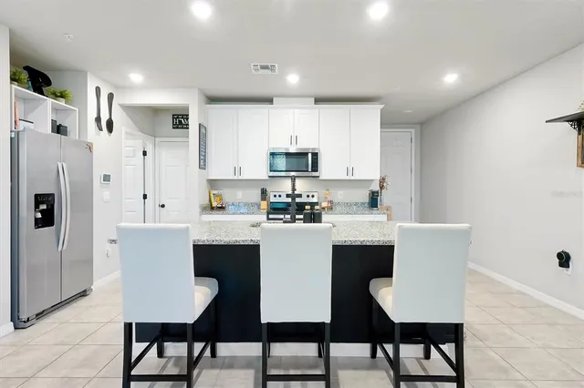 a kitchen with stainless steel appliances a white table chairs and a refrigerator