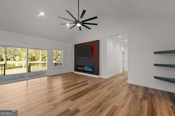 a view of an empty room with glass door and wooden floor