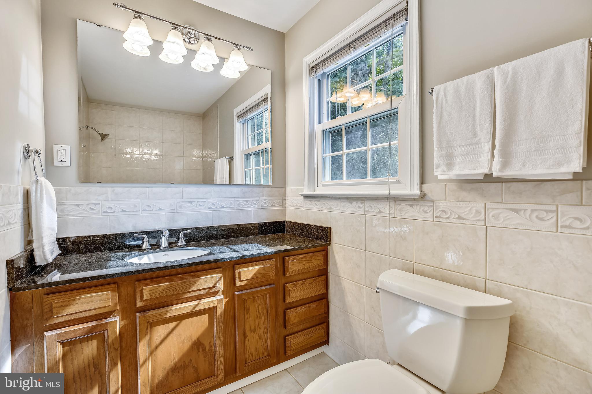1593 Kimblewick Road Potomac, MD 20854 - Photo 28 of 45 a bathroom with a granite countertop sink a toilet a mirror and a window