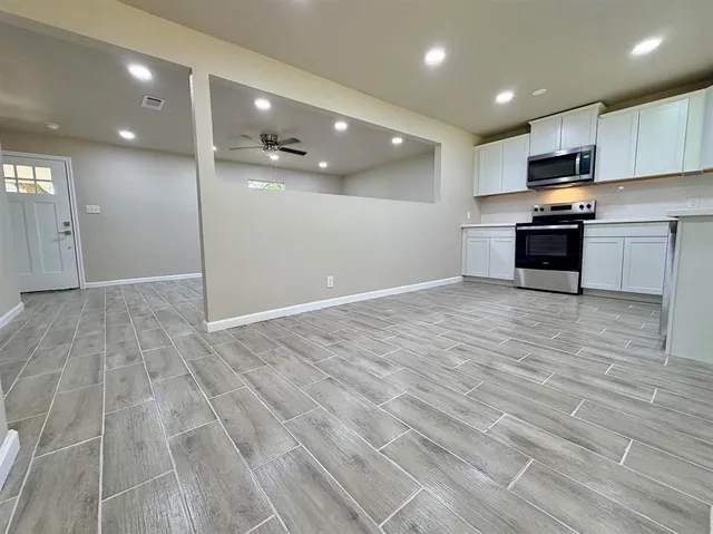 a view of kitchen with kitchen island granite countertop a stove top oven a sink and a counter space