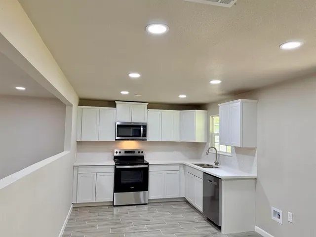 a kitchen with a sink a counter top space stainless steel appliances and cabinets