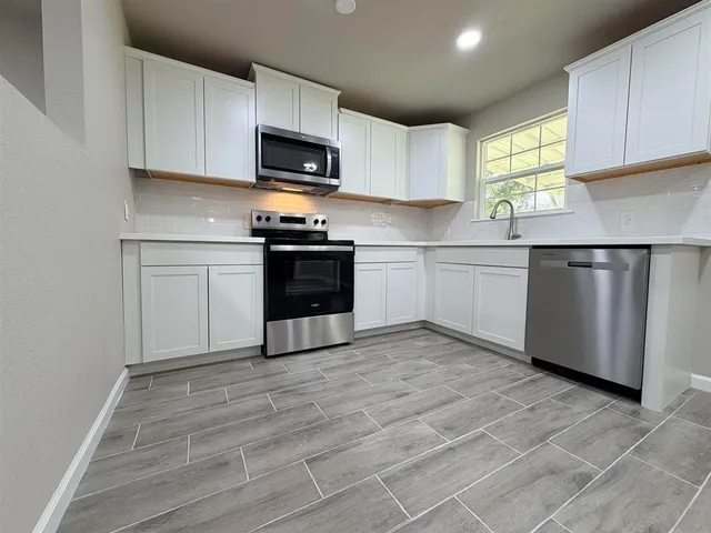 a kitchen with granite countertop a sink cabinets and stainless steel appliances