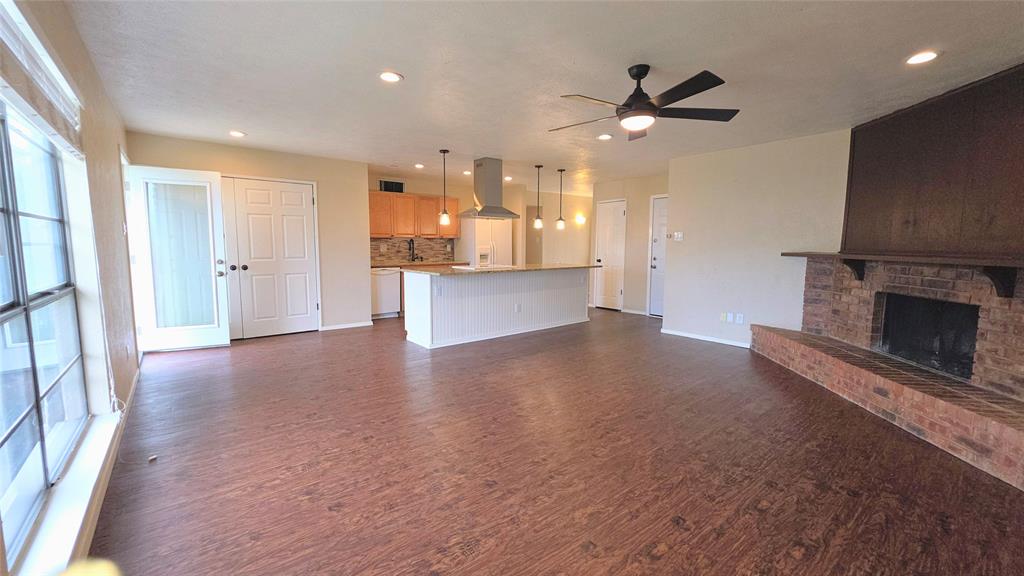 731 Leading Lane Allen, TX 75002 - Photo 4 of 18 a view of a living room a kitchen with a fireplace a ceiling fan and wooden floor