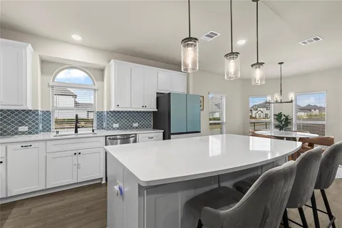 a kitchen with a dining table chairs sink and cabinets