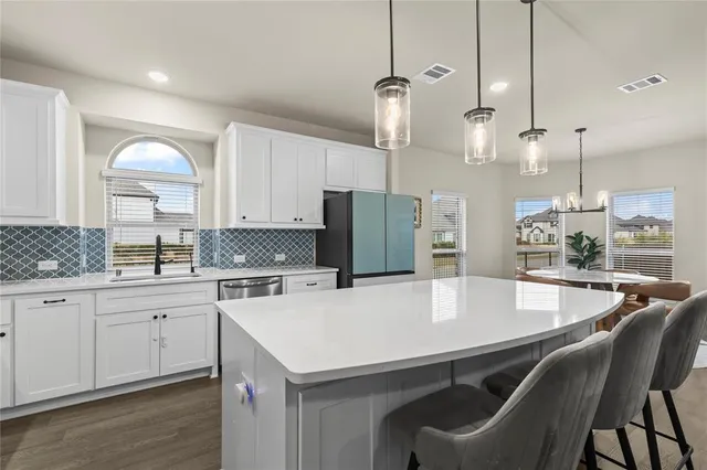 a kitchen with a dining table chairs sink and cabinets