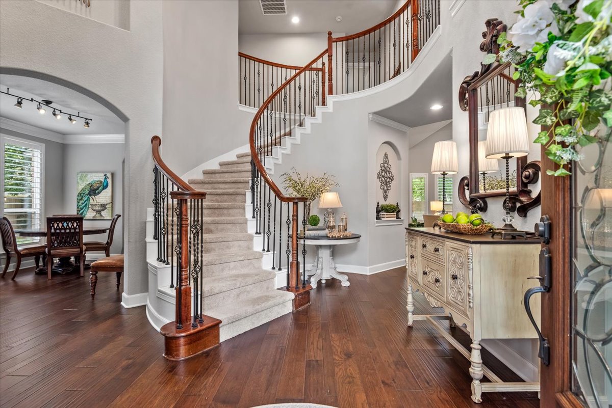 15519 Stallion Point Circle Cypress, TX 77429 - Photo 4 of 37 Elegant entryway featuring hardwood floors and a grand curved staircase with carpeted steps and iron balusters