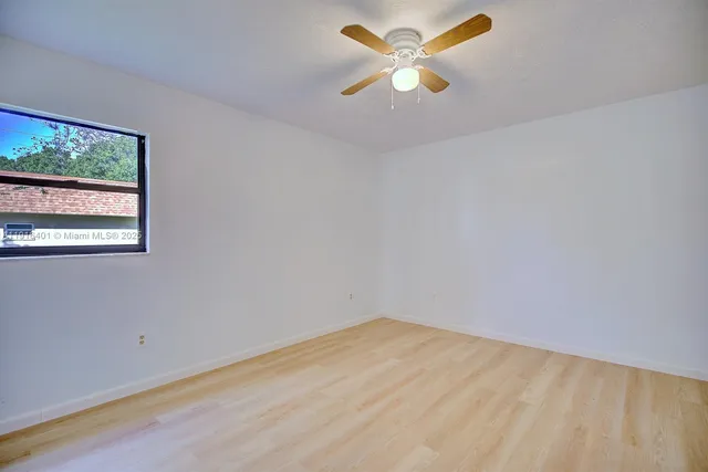 an empty room with a window and a ceiling fan