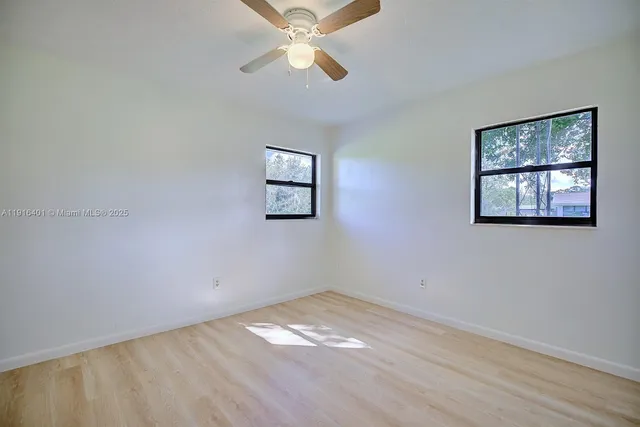 a view of empty room with wooden floor and fan