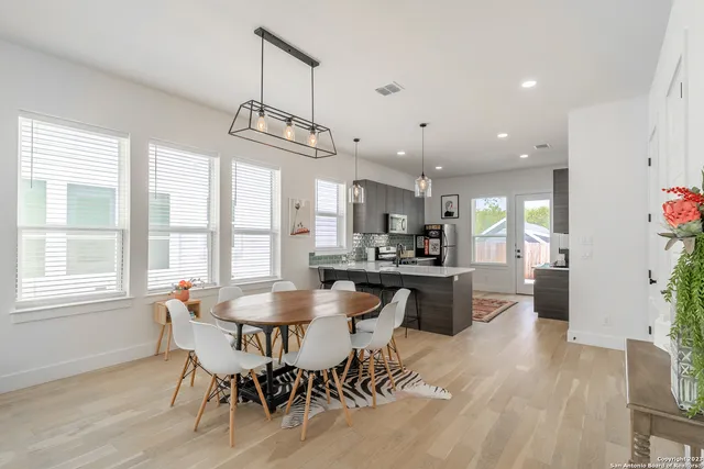 a dining room with wooden floor a chandelier a wooden table and chairs