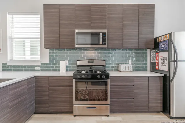 a kitchen with stainless steel appliances granite countertop wooden cabinets stove top oven and sink