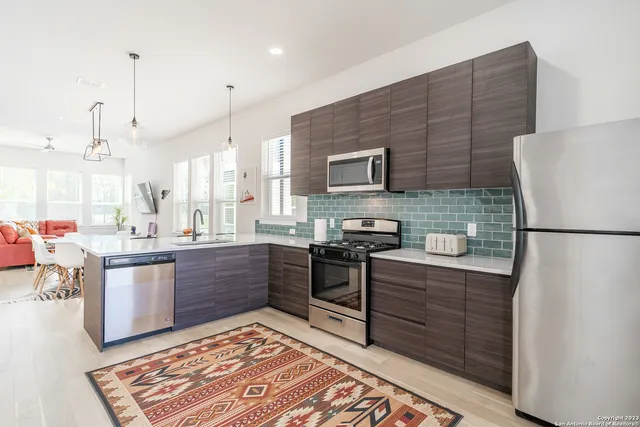 a kitchen with stainless steel appliances kitchen island granite countertop a sink stove and refrigerator