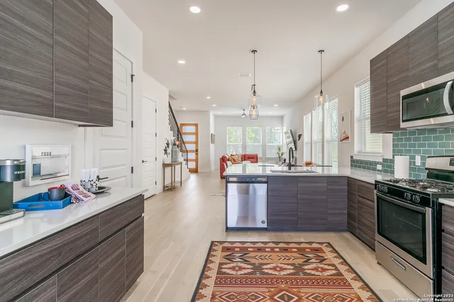 a large kitchen with stainless steel appliances kitchen island granite countertop a stove a sink dishwasher and a wooden cabinets