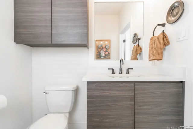 a bathroom with a toilet sink vanity and mirror