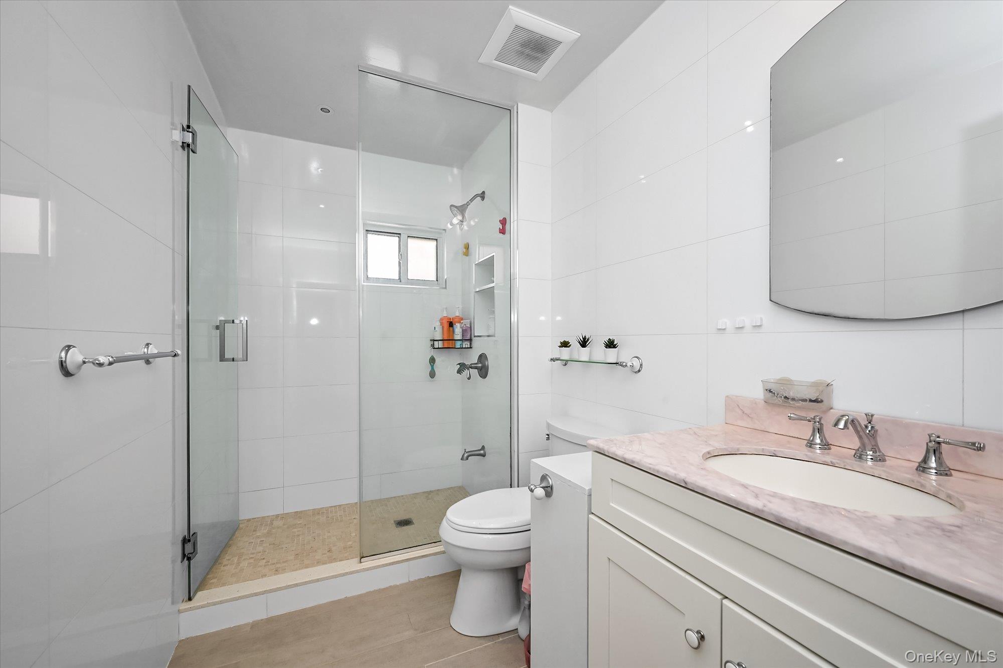 87-71 111th Street Queens, NY 11418 - Photo 14 of 17 a bathroom with a granite countertop sink a toilet and a shower