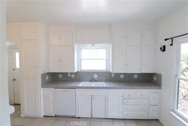 a kitchen with granite countertop white cabinets and sink
