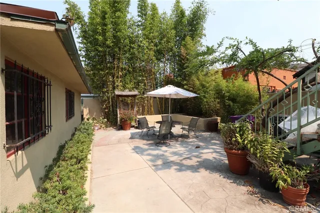 a view of a patio with table and chairs potted plants and large tree