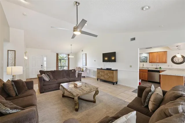 a living room with furniture kitchen view and a flat screen tv