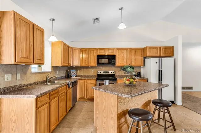 a kitchen with stainless steel appliances granite countertop a stove top oven a refrigerator a sink dishwasher and white cabinets with wooden floor