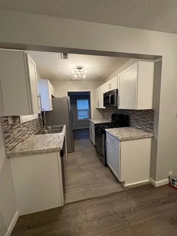 a view of a kitchen with a sink stove window and wooden floor