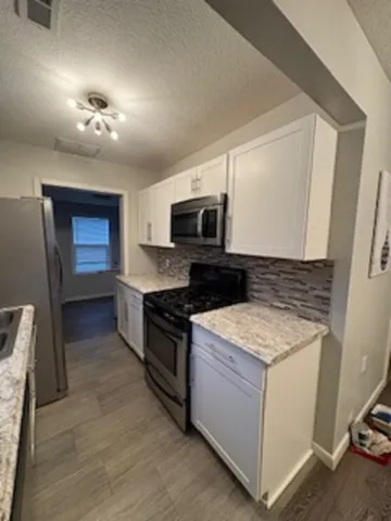 a kitchen with granite countertop a sink and a stove top oven with wooden floor