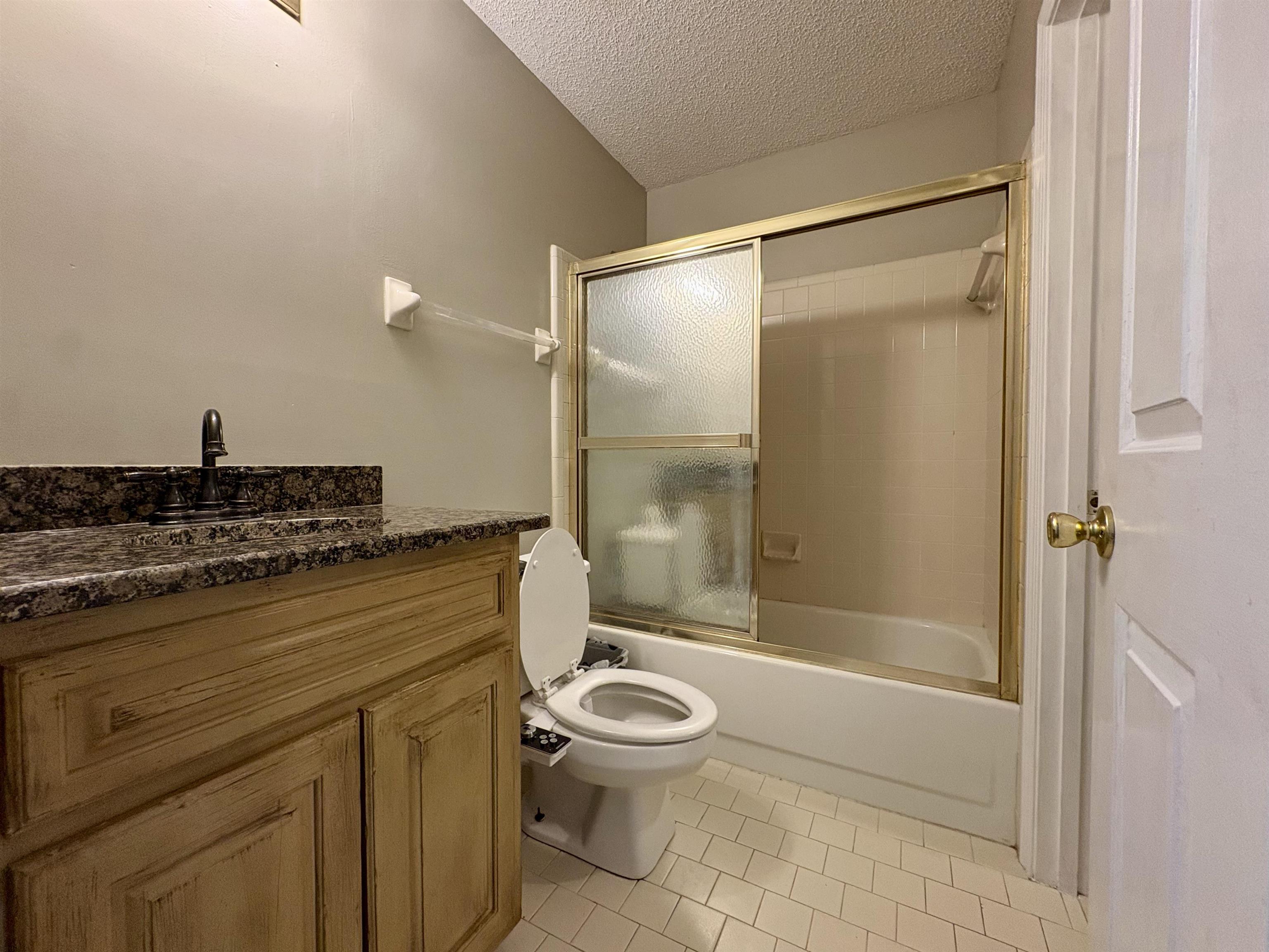 3507 Chowning Road Memphis, TN 38135 - Photo 13 of 17 Full bath featuring a textured ceiling, vanity, light tile patterned floors, and combined bath / shower with glass door