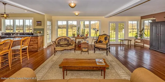 a living room with furniture a wooden floor and floor to ceiling windows
