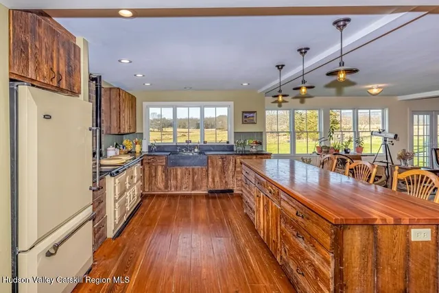 a kitchen with stainless steel appliances granite countertop a refrigerator a sink dishwasher a stove and white countertops with wooden floor