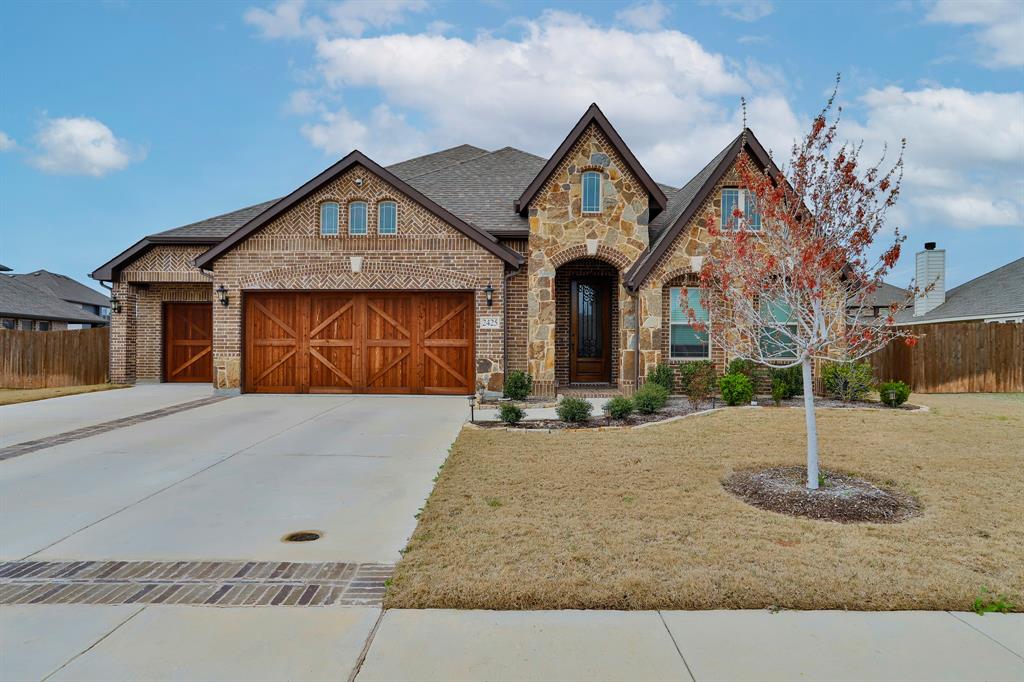 View of front of property featuring brick siding, stone siding, concrete driveway, and a garage