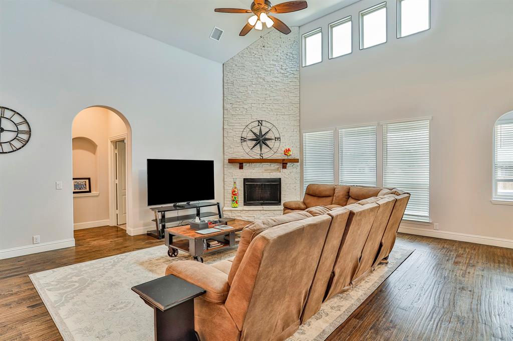 2425 Turning Leaf Lane Midlothian, TX 76065 - Photo 16 of 29 Living room with dark wood-style flooring, arched walkways, high vaulted ceiling, a ceiling fan, and a fireplace