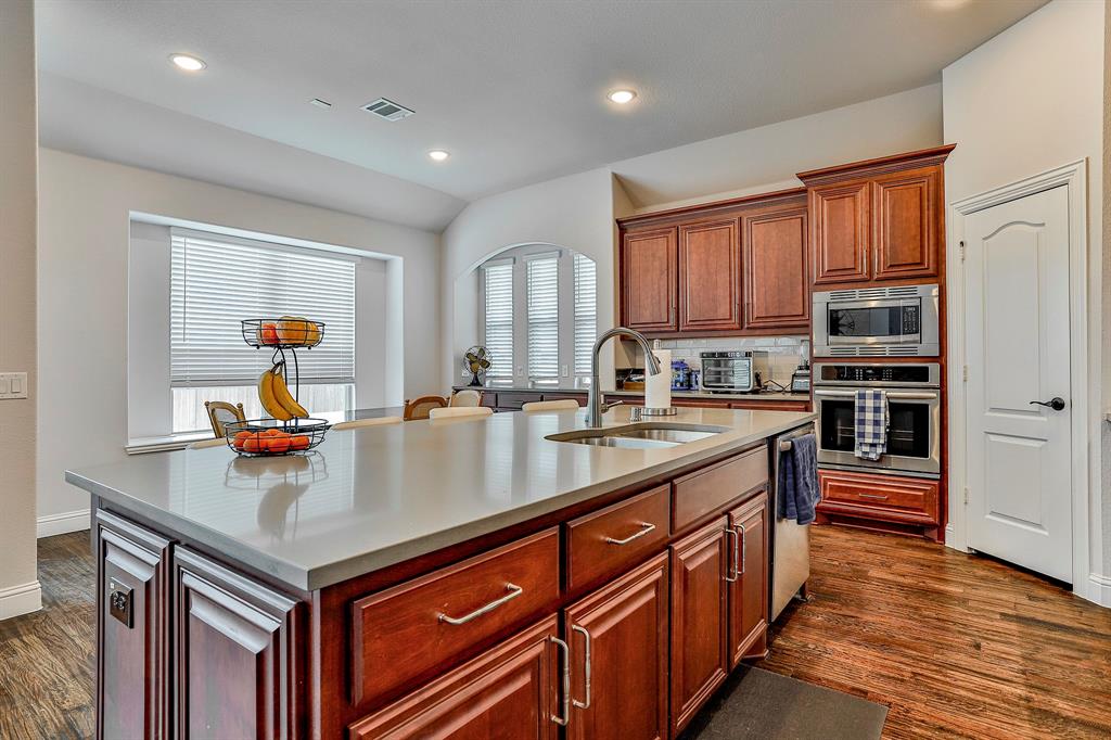 2425 Turning Leaf Lane Midlothian, TX 76065 - Photo 17 of 29 Kitchen with appliances with stainless steel finishes, brown cabinets, dark wood finished floors, a kitchen island with sink, and recessed lighting