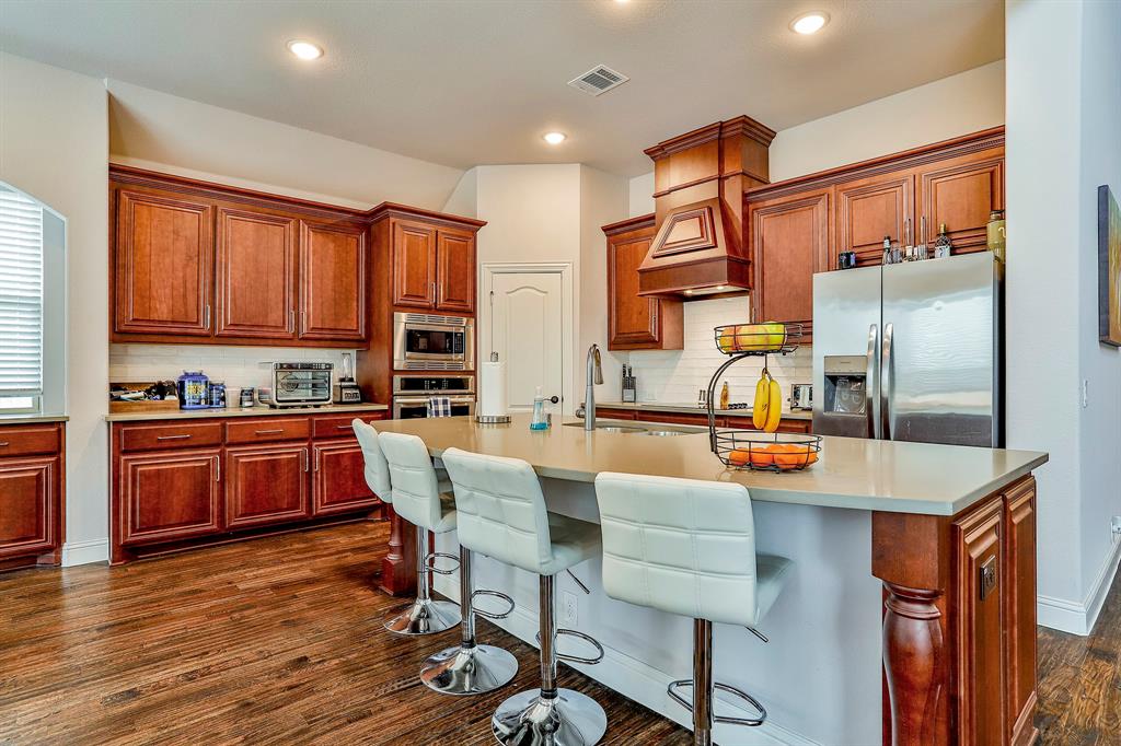 2425 Turning Leaf Lane Midlothian, TX 76065 - Photo 18 of 29 Kitchen featuring appliances with stainless steel finishes, a kitchen breakfast bar, tasteful backsplash, dark wood-style floors, and recessed lighting